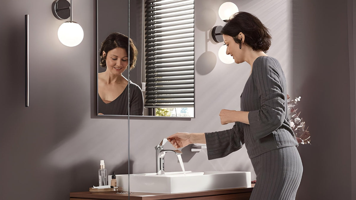 Mulher utilizando torneira de banheiro moderna e cromada em cuba branca de design premium.