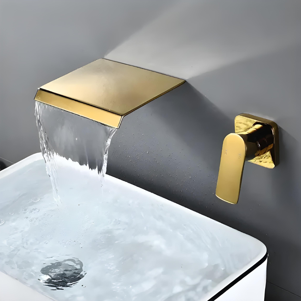 Torneira de parede cascata monocomando para banheiro Milon em dourado com água fluindo na cuba.