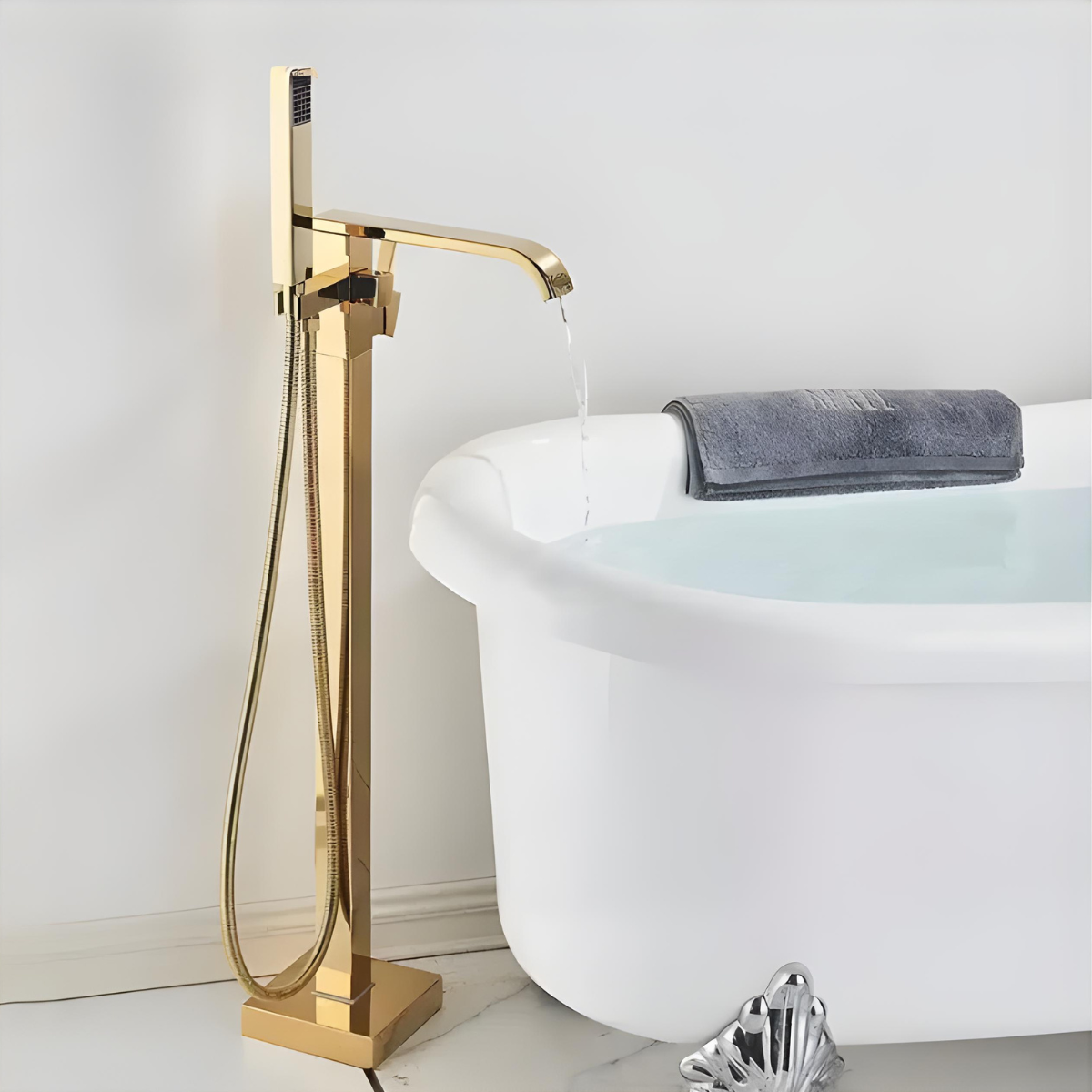 Misturador de piso monocomando dourado Venere da Homedeccori para banheira de imersão branca.