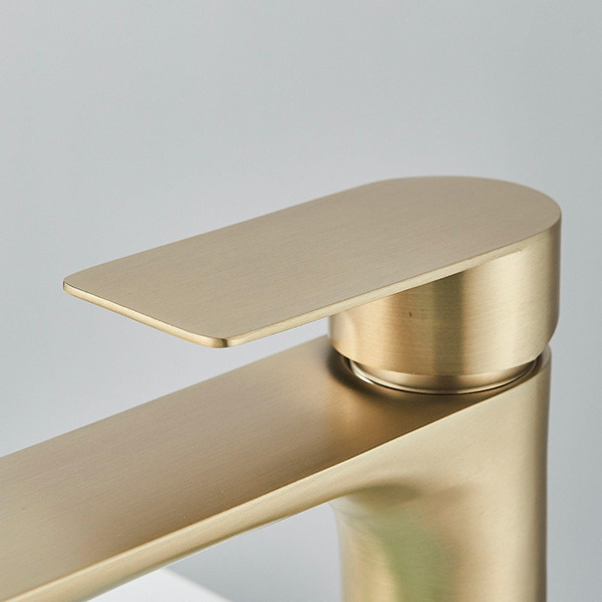 Detalhe do acionador da torneira para banheiro monocomando de bancada Tocco em dourado fosco.