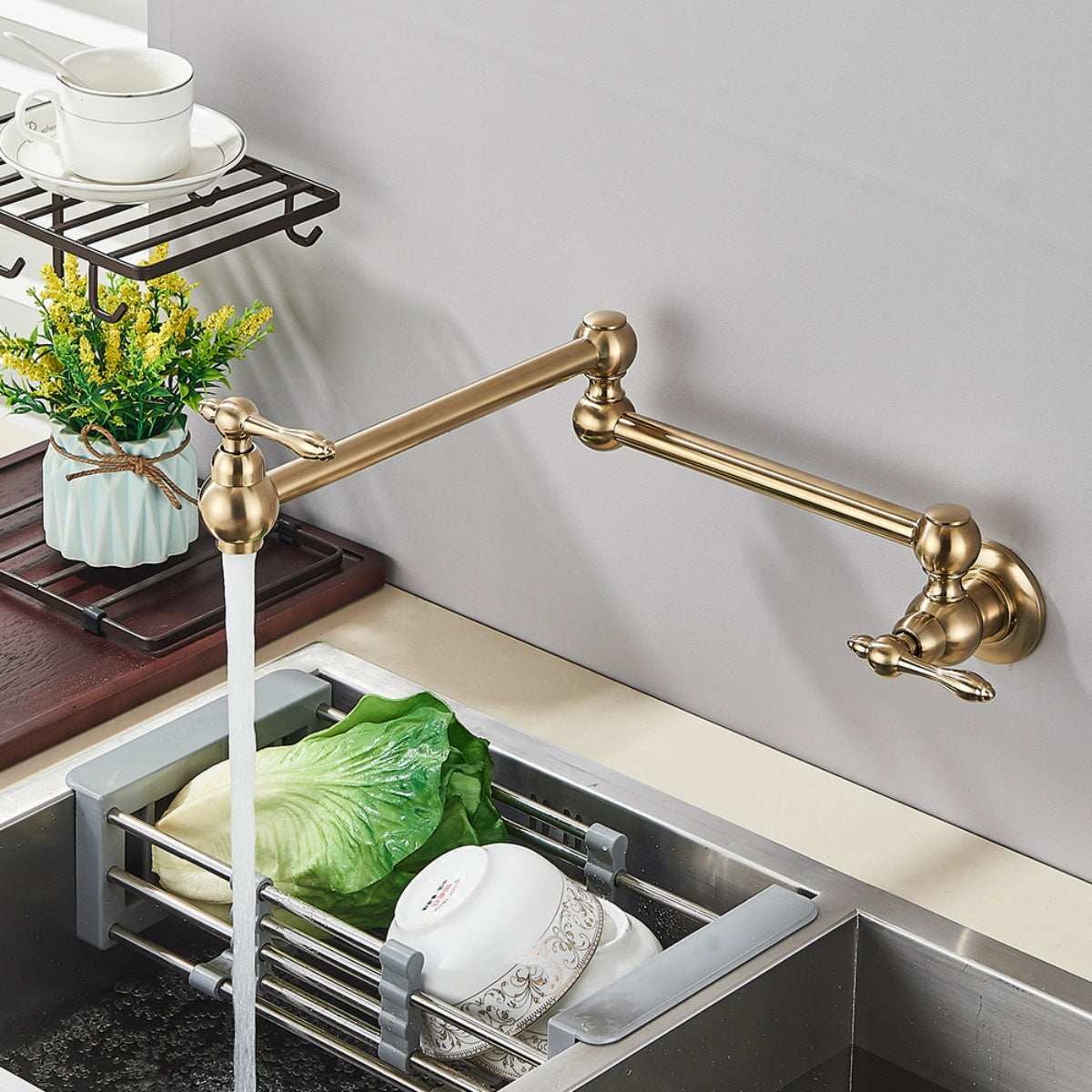 Torneira Articulada Cozinha de Parede Inox Veneza da Homedeccori em tom dourado com água fluindo.