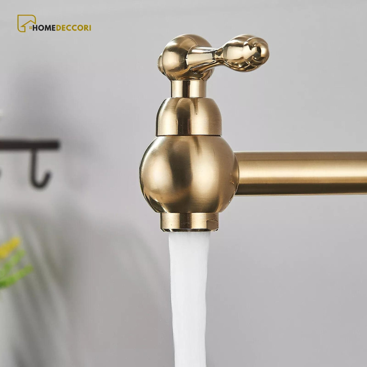 Torneira articulada de parede Homedeccori em inox dourado com água fluindo.