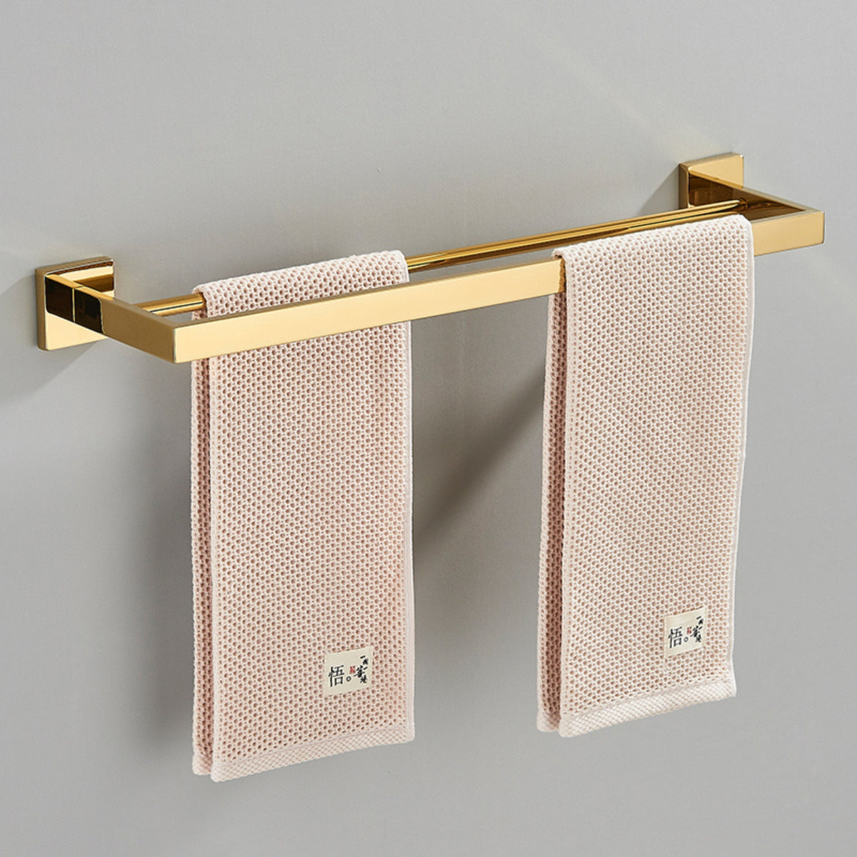 Toalheiro dourado de luxo Homedeccori com toalhas rosa claro.